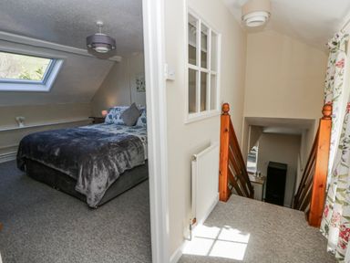 A bedroom with a bed and a staircase at Penlone Cottage in Rhayader
