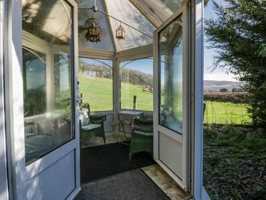 A conservatory with chairs and a table at Penlone Cottage in Rhayader