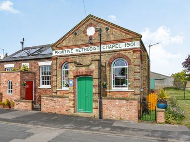 Front view of a brick chapel with green door and arched windows with stained glass at The New Chapel in Great Hatfield near Hornsea