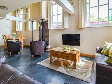 A living room with leather sofas a coffee table with tea set and a dining area with wooden table and chairs at The New Chapel Great Hatfield near Hornsea