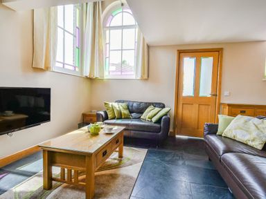 A living room with two leather sofas a wooden coffee table and a TV on the wall at The New Chapel in Great Hatfield near Hornsea