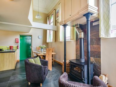 A dining area with table and chairs next to a wood burning stove and armchairs at The New Chapel in Great Hatfield near Hornsea