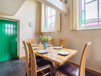 A dining room with a wooden table set with plates and glasses and a green door at The New Chapel in Great Hatfield near Hornsea