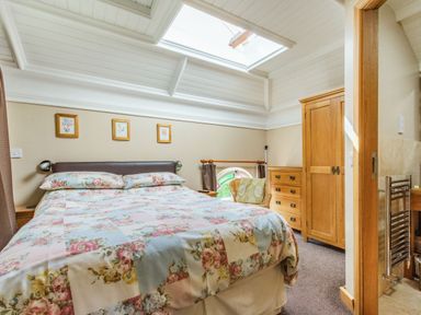 A bedroom with a double bed floral bedding wooden wardrobe and chest of drawers at The New Chapel in Great Hatfield near Hornsea