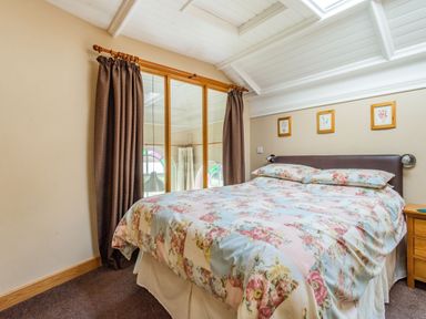 A bedroom with a floral bedspread a wooden nightstand and framed pictures on the wall at The New Chapel in Great Hatfield near Hornsea