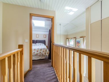 A hallway with carpet and wooden railing leading to a bedroom with a bed and skylight at The New Chapel in Great Hatfield near Hornsea