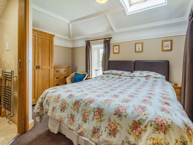 A bedroom with a floral bedspread a wooden wardrobe a chest of drawers and a wicker chair at The New Chapel Great Hatfield near Hornsea