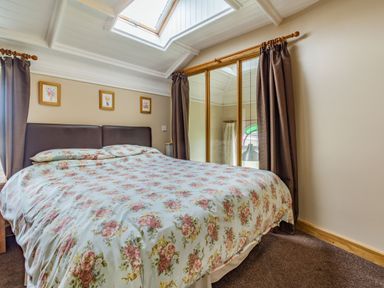A bedroom with a bed covered by floral bedding and mirrored wardrobes at The New Chapel in Great Hatfield near Hornsea