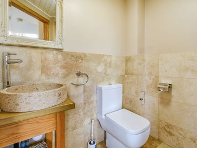 A bathroom with a stone sink a toilet and mirror at The New Chapel in Great Hatfield near Hornsea