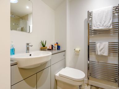 A bathroom with a sink cabinet toilet and heated towel rack with towels at 3 Tyn Y Mynydd in Penmachno