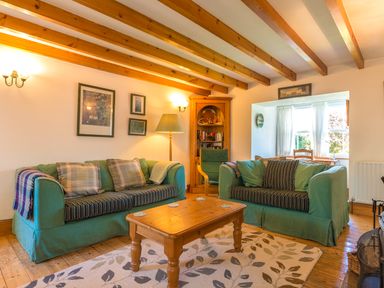 A living room with two green sofas a wooden coffee table and a bookshelf at Townfoot Cottage in Elsdon near Otterburn