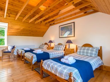 A bedroom with three single beds with blue and plaid bedding wooden ceiling and flooring at Townfoot Cottage Elsdon near Otterburn