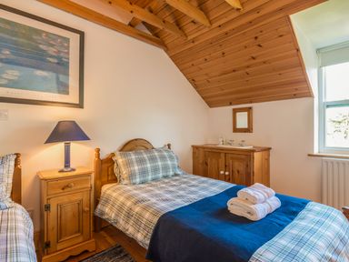 A bedroom with two single beds wooden furniture and a window at Townfoot Cottage Elsdon near Otterburn