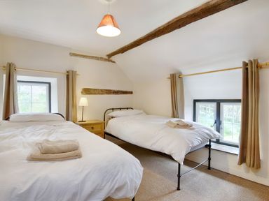 A bedroom with two single beds a nightstand lamp and two windows at The Birches in Hay-on-Wye