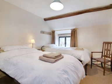 A bedroom with two single beds and an armchair near a window at The Birches in Hay-on-Wye
