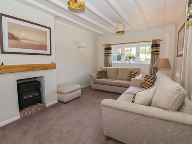 A living room with two sofas a fireplace a window with curtains and a lamp at Waggoner's Cottage Bessingby near Bridlington