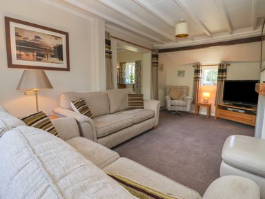 A living room with sofas armchair television and lamps at Waggoner's Cottage in Bessingby near Bridlington