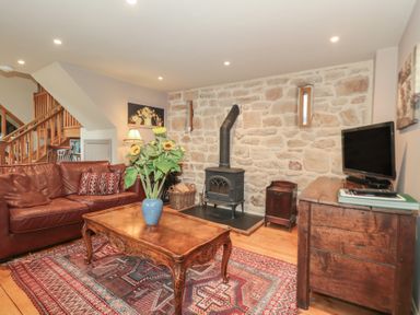 A living room with a sofa, coffee table, and wood stove at The Lodge Farm Barn in Deepdean near Ross-on-Wye