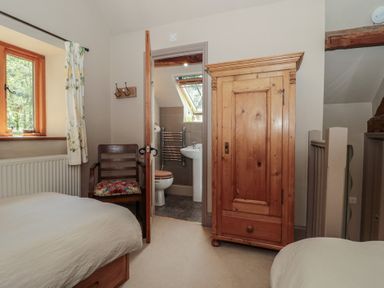 A bedroom with a bed, wardrobe and connecting bathroom at The Lodge Farm Barn in Deepdean near Ross-on-Wye