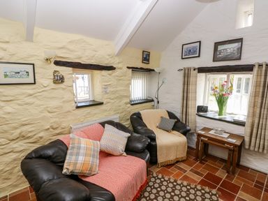 A sitting room with two leather chairs a wooden table and framed pictures on the walls at Ffynnon Tom in Trefin near St Davids