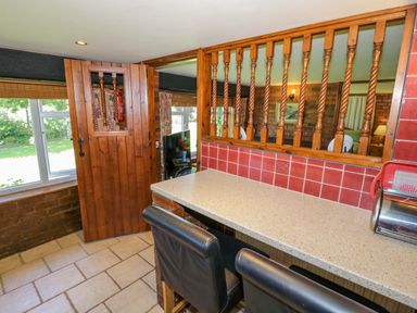 A kitchen with a serving window and bar stools at Severn Bank Lodge Astley Burf near Stourport-on-Severn