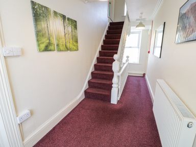 A carpeted hallway with stairs and framed pictures on the wall at Halford Hill in Llanberis