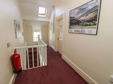 A hallway with stairs and a skylight window a fire extinguisher on the wall and a Wales poster at Halford Hill in Llanberis