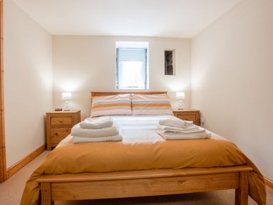 A bedroom with a wooden bed and two bedside tables with lamps at Hendre Cottage Bronaber near Trawsfynydd
