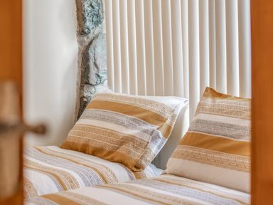 A close up of beds with patterned bedding and pillows in a room with vertical blinds at Hendre Cottage in Bronaber near Trawsfynydd