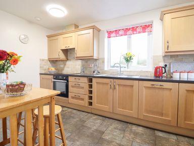 A kitchen with wooden cabinets and a table in Bryn Re, Trawsfynydd near Llan Ffestiniog and Dolgellau