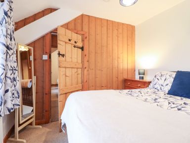 A bedroom with a bed, nightstand, and a mirror at Bryn Re Trawsfynydd near Llan Ffestiniog and Dolgellau