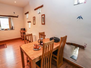 A dining area with wooden table and chairs croissants and a coffee press on the table small windows and wall decorations at The Hayloft in Newlands near Braithwaite and Keswick