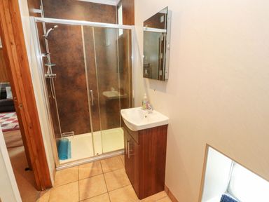 A bathroom with a shower enclosure and a sink with a mirror above at The Hayloft in Newlands near Braithwaite and Keswick
