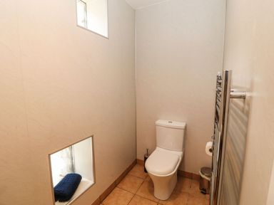 A small bathroom with a toilet a towel on a recessed shelf a radiator and a trash bin at The Hayloft in Newlands near Braithwaite and Keswick