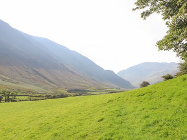 A grassy valley with hills on both sides and a few trees on the right at The Hayloft in Newlands near Braithwaite and Keswick