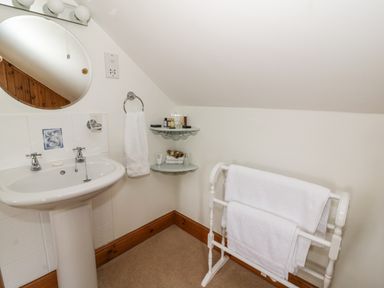 A bathroom corner with a pedestal sink mirror towel ring with towel and towel rack with towels at Tangaer Cottage in Cellan near Lampeter