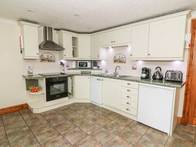 A kitchen with white cabinets appliances microwave toaster and kettle at Tangaer Cottage in Cellan near Lampeter