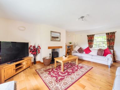 A living room with a sofa a coffee table a television and a fireplace at Old Rectory Cottages Aberhafesp near Newtown