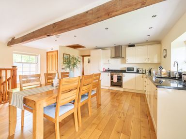 A kitchen with wooden dining table and chairs white cabinets and wooden floor at Old Rectory Cottages Aberhafesp near Newtown