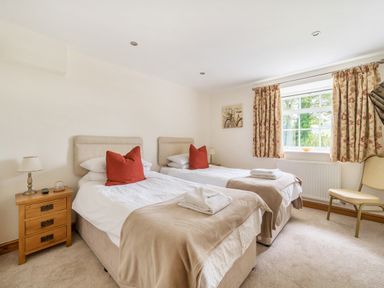 A bedroom with two single beds bedside tables and a window with curtains at Old Rectory Cottages Aberhafesp near Newtown