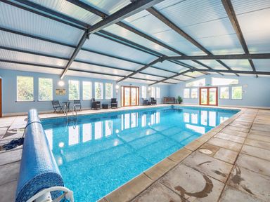 An indoor swimming pool with chairs and tables along the walls at Old Rectory Cottages Aberhafesp near Newtown