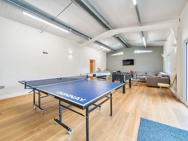 A game room with a ping pong table foosball table sofa and television at Old Rectory Cottages Aberhafesp near Newtown