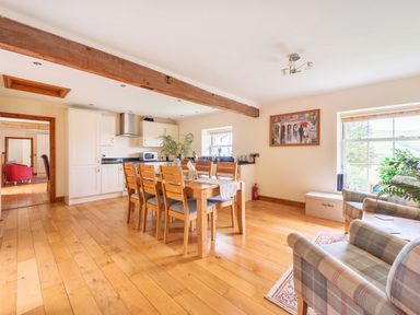 A kitchen dining area with wooden table and chairs near windows and seating area at Old Rectory Cottages Aberhafesp near Newtown