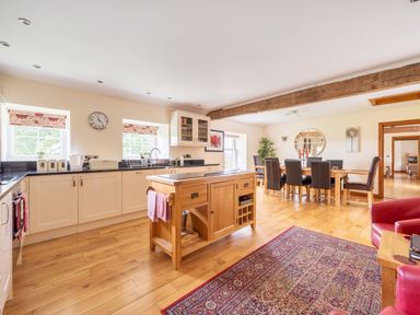 A kitchen and dining area with wooden flooring a wooden kitchen island and a dining table with chairs at Old Rectory Cottages Aberhafesp near Newtown