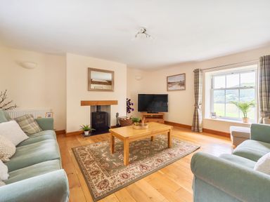A living room with sofas a wooden coffee table a fireplace and a television at Old Rectory Cottages Aberhafesp near Newtown
