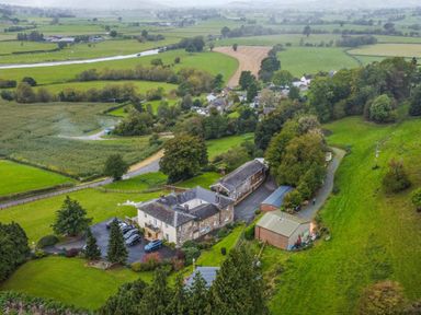 Aerial view of a countryside property with multiple buildings surrounded by green fields and trees at Old Rectory Cottages Aberhafesp near Newtown