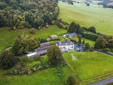 An aerial view of a countryside property with multiple buildings surrounded by trees and fields at Old Rectory Cottages Aberhafesp near Newtown