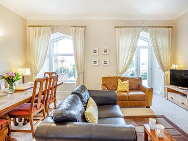 A living room with two sofas a wooden dining table with chairs and a television at Menai View in Llanfairpwllgwyngyll near Beaumaris