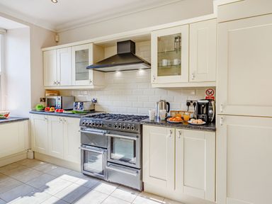 A kitchen with white cabinets a double oven a stovetop a toaster a kettle a coffee machine and fresh produce on the counters at Menai View in Llanfairpwllgwyngyll near Beaumaris