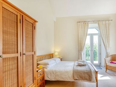 A bedroom with a wooden bed and wardrobe next to French doors at Menai View in Llanfairpwllgwyngyll near Beaumaris
